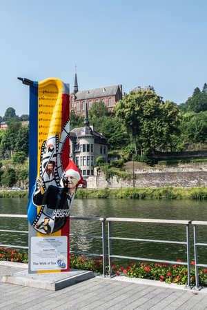 Dinant, Belgium - June 26, 2019: Colurful Memorial monumemt for composer Vladimir Cosma in shape of Saxophone along Meuse River under blue sky. Green foliage in back.のeditorial素材