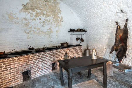Dinant, Belgium - June 26, 2019: Inside Citadelle. Part of historic army kitchen with battery of stoves, pots and pans, and a killed boar hanging on the white pained wall.のeditorial素材