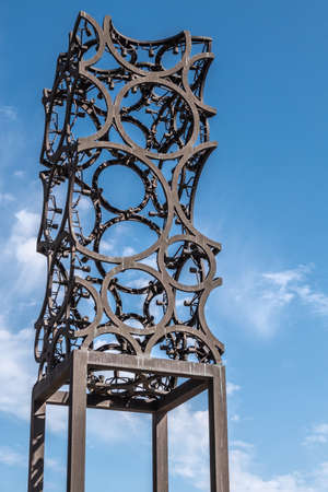 Amsterdam, the Netherlands - June 30, 2019: Closeup of tall rusted artwork, sculpture of metal circles welded together and set against blue sky with some white clouds.のeditorial素材