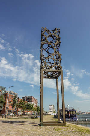 Amsterdam, the Netherlands - June 30, 2019: Tall rusted artwork, sculpture of metal circles welded together and set against blue sky with some white clouds on IJdok.のeditorial素材