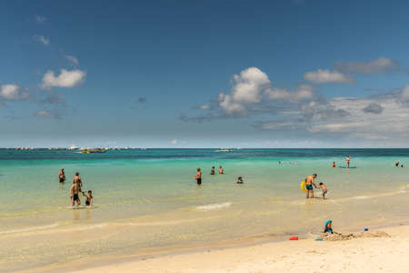 Balabag, Boracay Island, Philippines - March 4, 2019: White beach shows sand and azure sea with plenty boats in distance and people in water.のeditorial素材