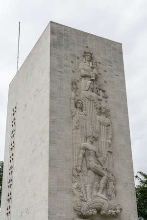 Manila, Philippines - March 5, 2019: American Cemetery and Memorial park. Closeup of fresco on gray stone memorial tower against silver sky and some green foliage.のeditorial素材