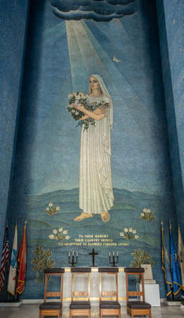 Manila, Philippines - March 5, 2019: American Cemetery and Memorial park. Inside mausoleum building. Image of woman with flowers against blue as backdrop for altar. American flags, candles and cross.のeditorial素材