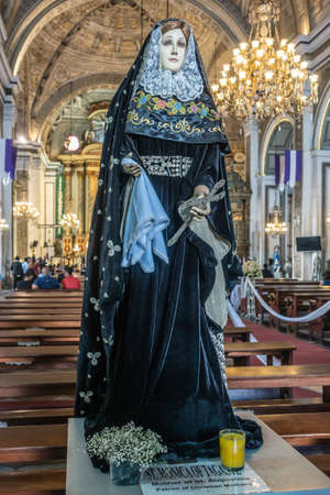 Manila, Philippines - March 5, 2019: San Augustin Church. Live size statue, dressed in blue and gold, of Saint Monica of Hippo in back of church. Far end is chancel with sitting people.のeditorial素材