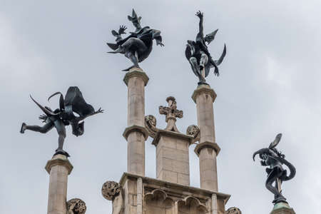 Gent, Flanders, Belgium -  June 21, 2019: Closeup of Dark Bronze Four dancers statue on beige gable top of Metselaarshuis, Masons Guild House against light blue sky.のeditorial素材