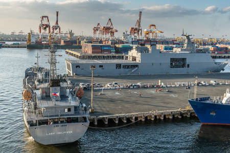 Manila, Philippines - March 5, 2019: Navy AF-81 Lake Caliraya ship and large gray Navy LD-601 BRP Tarlac on other side of pier under light blue sky. Walls of containers and cranes in back.のeditorial素材