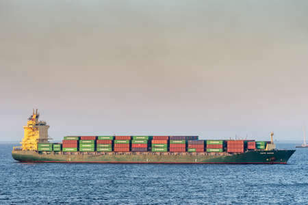Manila, Philippines - March 5, 2019: Closeup. Evening twilight shines on green and red Cape Mayor container ship sailing into South Harbor.のeditorial素材