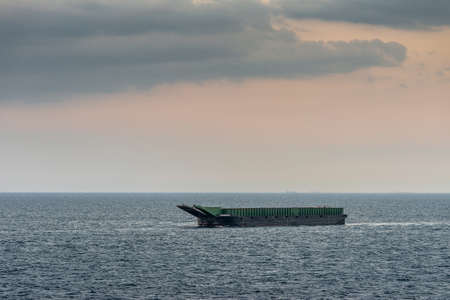 Manila, Philippines - March 5, 2019: Closeup. Evening falls on green and black large barge Kalusugan 2, anchored in the bay off South Harbor.のeditorial素材