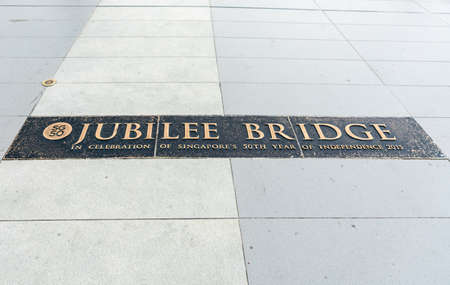 Singapore - March 20, 2019: Closeup of sign in surface of Jubilee Pedestrian bridge linking Merlion with Esplanade Theatres. Copper on white tiles. Independence remembrance.のeditorial素材
