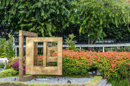 Singapore - March 20, 2019: Gold colored Window of Hope statue on Collyer Quay among red flowers and green foliage.のeditorial素材