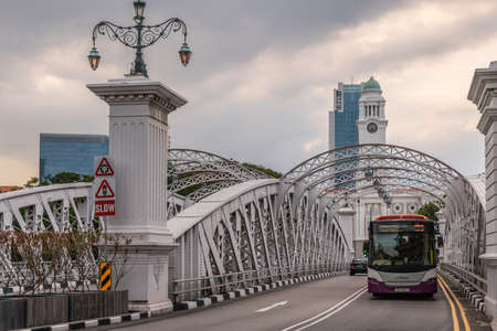 Singapore - March 20, 2019: Public bus rides over historic Anderson bridge with Victoria Theatre clock tower in back under cloudscape.のeditorial素材