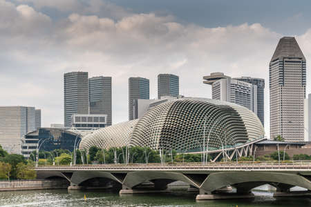 Singapore - March 20, 2019: Skyscrapers towering over Esplande Theatres domes , park and bridge over Singapore River under cloudscape.のeditorial素材
