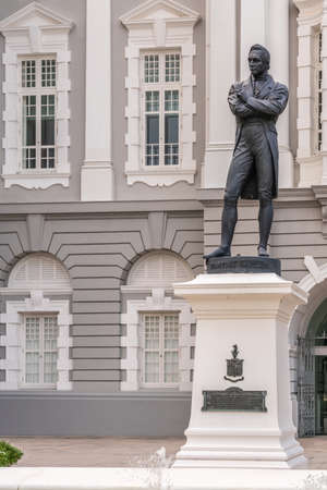 Singapore - March 20, 2019: Black bronze statue on white pedestal of Stamford Raffles in front of white and gray facade of Victoria Theatres.のeditorial素材