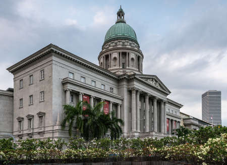 Singapore - March 20, 2019: Historic gray with green dome building of National Gallery under blueish sky with green foliage on the fringes.のeditorial素材