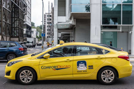 Singapore - March 20, 2019: Closeup of Comfort Delgro yellow taxi in street scene with traffic and people,のeditorial素材