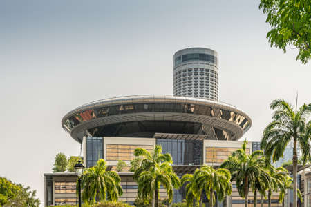 Singapore - March 21, 2019: From Singapore River. The Supreme Court spaceship-like circular top construction with Swissotel The Stamford tower behind. Green tree foliage in front.のeditorial素材