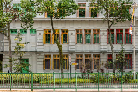 Singapore - March 21, 2019: Gray facade with colorful window frames of historic old Hill Street Police Station along River Valley Road. Lots of foliage in front.のeditorial素材