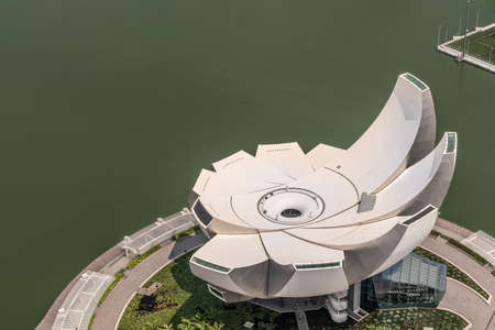 Singapore - March 21, 2019: Shot from Sands roof. Birds eye view on white circular lotus of shell like ArtScience Museum. Greenish Marina water.のeditorial素材