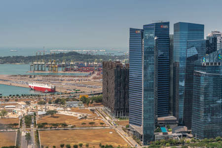 Singapore - March 21, 2019: Shot from Sands roof. Birds eye view on sea with container port and part of Financial District under light blue sky.のeditorial素材