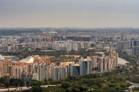 Singapore - March 21, 2019: Shot from Sands roof. Birds eye closeup of red roofed Tanjong complex neighborhood with tens of skyscrapers in back. Green added by parks.のeditorial素材