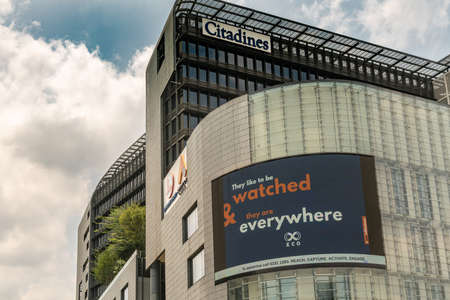 Singapore - March 21, 2019: At Citadines, a giant electronic screen advertisement board covers part of yellowish wall promoting XCO marketing company. Cloudscape and green foliage.のeditorial素材
