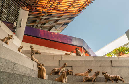 Singapore - March 22, 2019: Gardens by the Bay, the Flower Dome. Large group of brown lion statues on steps outside the dome under blue sky and brown awning.のeditorial素材
