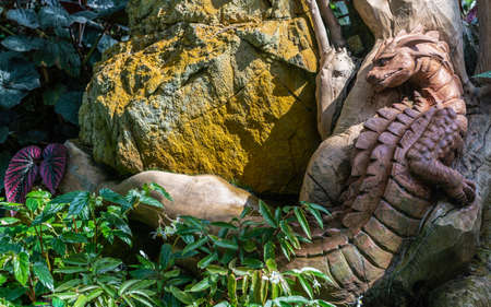 Singapore - March 22, 2019: Gardens by the Bay, the Cloud Forest Dome. Large brown wooden crocodile monster statue crawls through dense green vegetation and yellow rock.のeditorial素材