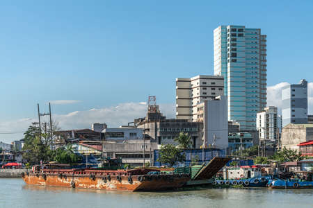 Manila, Philippines - March 5, 2019: Outside Fort Santiago. Barges and skyscrapers apartment buildings across Pasig River under blue sky.のeditorial素材