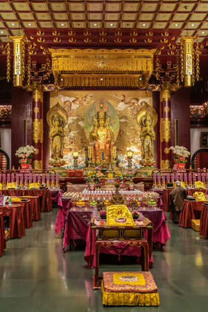 Singapore - March 22, 2019: Buddha Tooth Relic Temple in Chinatown. Main prayer room with seated Buddha Maitreya flanked by two Bodhisattvas. Lots of gold and maroon colors.のeditorial素材