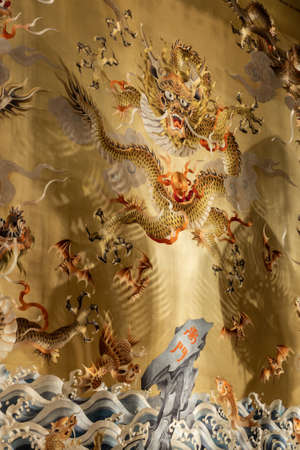 Singapore - March 22, 2019: Buddha Tooth Relic Temple in Chinatown. Closeup of part of reredos behind Medicine Buddha shows golden field with small and large monsters, fish and dragons.のeditorial素材