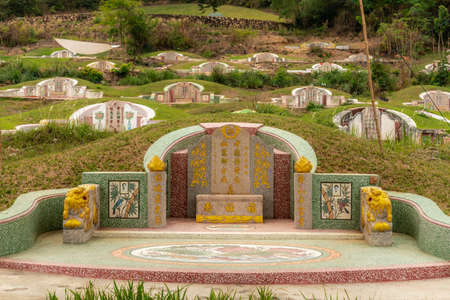 Bang Phra, Thailand - March 16, 2019: Chao Pho Khao Chalak Chinese Cemetery. Green-gold family grave with beige tombstone and colored Mandarin letters. covered by green lawn.のeditorial素材