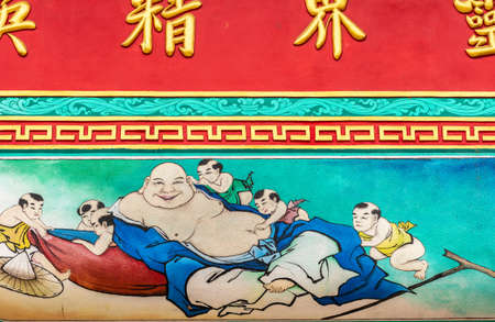 Bang Phra, Thailand - March 16, 2019: Chao Pho Khao Chalak Chinese Cemetery. Reunion hall and shrine for mourning families. Outer wall painting of Laughing Buddha with small kids.のeditorial素材