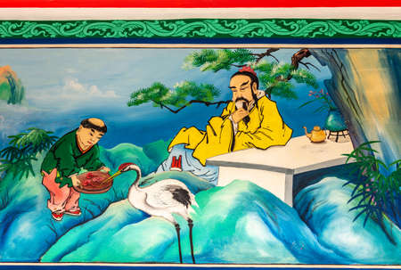 Bang Phra, Thailand - March 16, 2019: Chao Pho Khao Chalak Chinese Cemetery. Reunion hall and shrine for mourning families. Outer wall painting of crane bird fed by man under supervision of guru.のeditorial素材