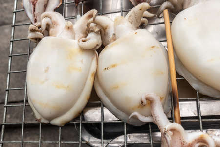 Chon Buri, Thailand - March 16, 2019: Closeup of large, white prepared, cooked squids on display at...
