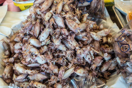 Chon Buri, Thailand - March 16, 2019: Closeup of Heap of white and brown squid on display at street market in Sukhumvit Road.の写真素材