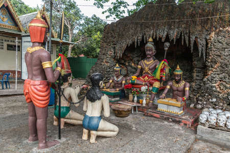 Bang Saen, Thailand - March 16, 2019: Garden of Hell in Wang Saensuk Buddhist Monastery. Captive couple is judged by devil king at arrival in hell. Gray cave and green foliage.の写真素材