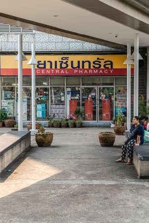 Bangkok city, Thailand - March 17, 2019: Central Pharmacy has its name on display in red and yellow band above large window showing lots of merchandise. People on bench in photo.のeditorial素材