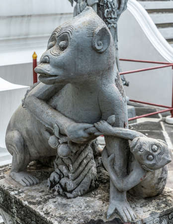 Bangkok city, Thailand - March 17, 2019: Monkey mother and offspring statue at bottom of Temple of Dawn, with white wall in back.の写真素材