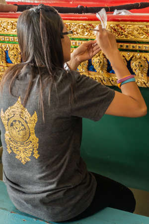 Bangkok city, Thailand - March 17, 2019: Royal Barge National Museum. Closeup of woman applying carefully with fine brush gold paint on side of Royal barge.のeditorial素材
