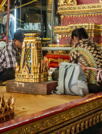 Bangkok city, Thailand - March 17, 2019: Royal Barge National Museum. Two workers maintain and correct the gold and red decorations on royal throne of royal barge.のeditorial素材