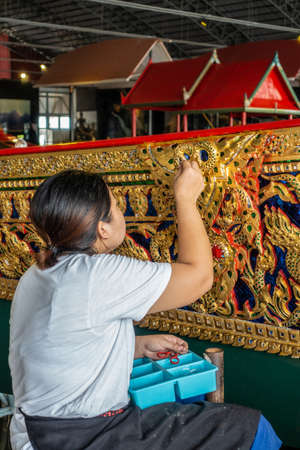 Bangkok city, Thailand - March 17, 2019: Royal Barge National Museum. Female worker applies gemstones on side of Royal Barge.のeditorial素材
