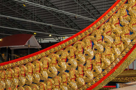 Bangkok city, Thailand - March 17, 2019: Royal Barge National Museum. Closeup of red and golden flank with deep blue spot of Royal Barge Anekchart Phu-Chong under dark roof.のeditorial素材