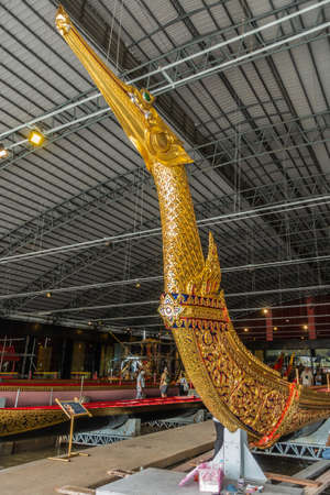 Bangkok city, Thailand - March 17, 2019: Royal Barge National Museum. Prow with figurehead of Royal barge Suphannahong shows golden head of charial reptile with green eye, in wider hall view.のeditorial素材