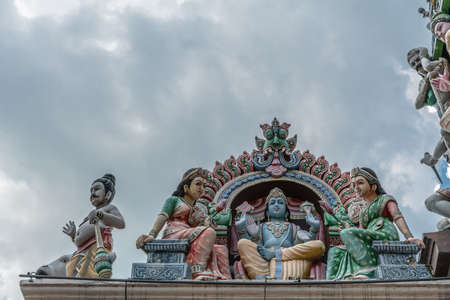 Singapore - March 22, 2019: Sri Mariamman Hindu Temple on South Bridge Road. Closeup of niche of blue Lord Vishnu with two wives, Lakshmi and Bhu, on side of Gopuram under dark cloudscape.のeditorial素材