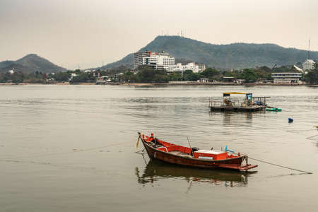 Si Racha, Thailand - March 16, 2019: Couple of small fishing vessels on flat gray water just off...