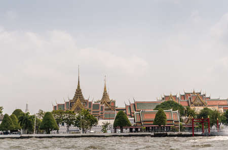 Bangkok city, Thailand - March 17, 2019: Chao Phraya River. National Grand Palace under light blue cloudscape and green foliage in front. Spires and special architecture.のeditorial素材