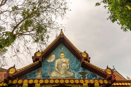Ko Samui Island, Thailand - March 18, 2019: Wat Khunatam Buddhist Temple and monastery. Painted on gable, image of monk Luang Por Deeng, saint of the temple. Silver sky and green foliage.の写真素材