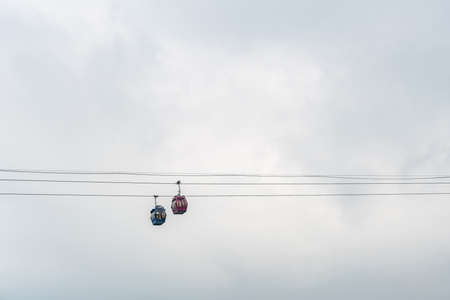 Nha Trang, Vietnam - March 11, 2019: Evening, Two aerial cable cabins against silve sky pass over port from mainland to tourist island.のeditorial素材