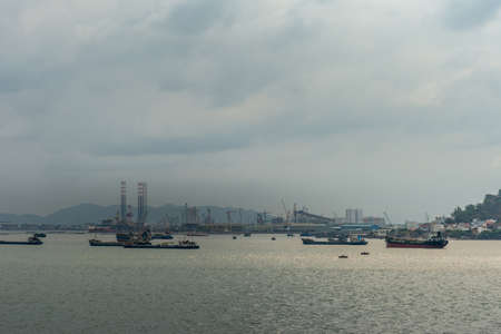 Vung Tau, Vietnam - March 12, 2019: Dark morning cloudscape over harbor area of the city with boat...