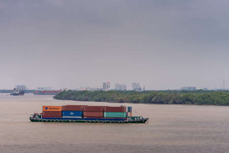 Long Tau River, Vietnam - March 12, 2019: Closeup of black and blue small river container boat on...
